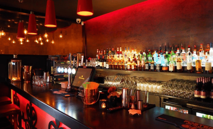 A selection of assorted liquor bottles displayed on a backlit bar shelf