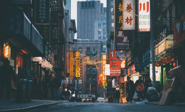 Busy street scene in NYC's Chinatown with colorful storefronts and traditional lanterns