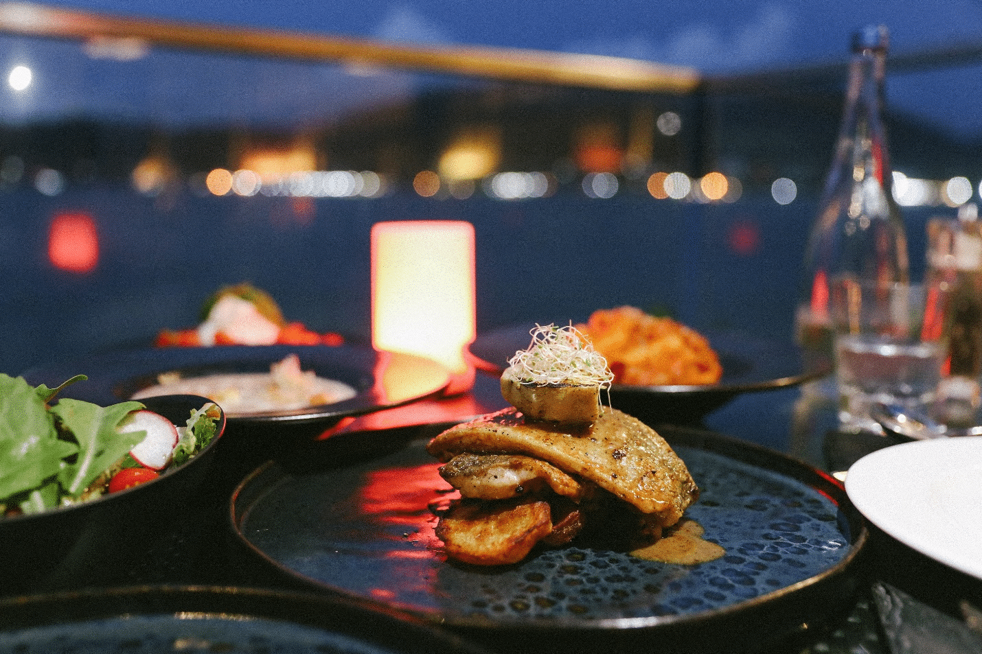 A plated meal with a bokeh background showcasing a glamorous NYC dinner cruise atmosphere