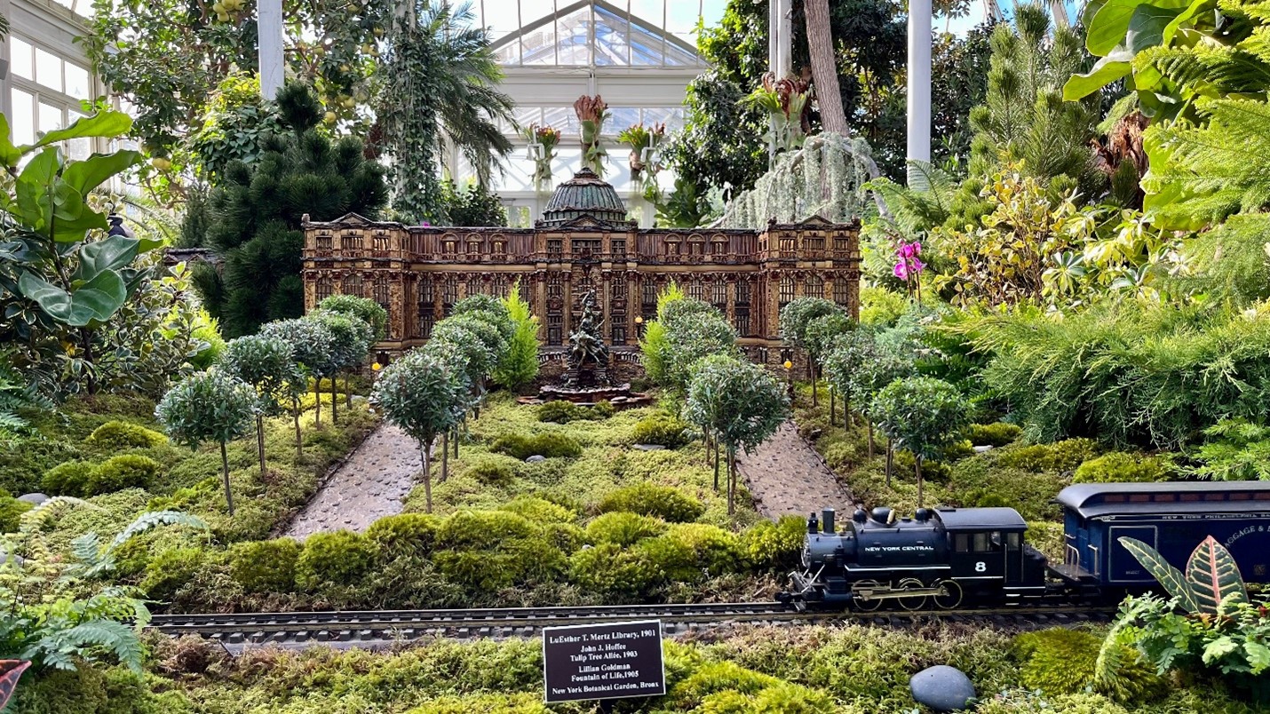 A blue model train in a mini-forest seen during a city trip to New York