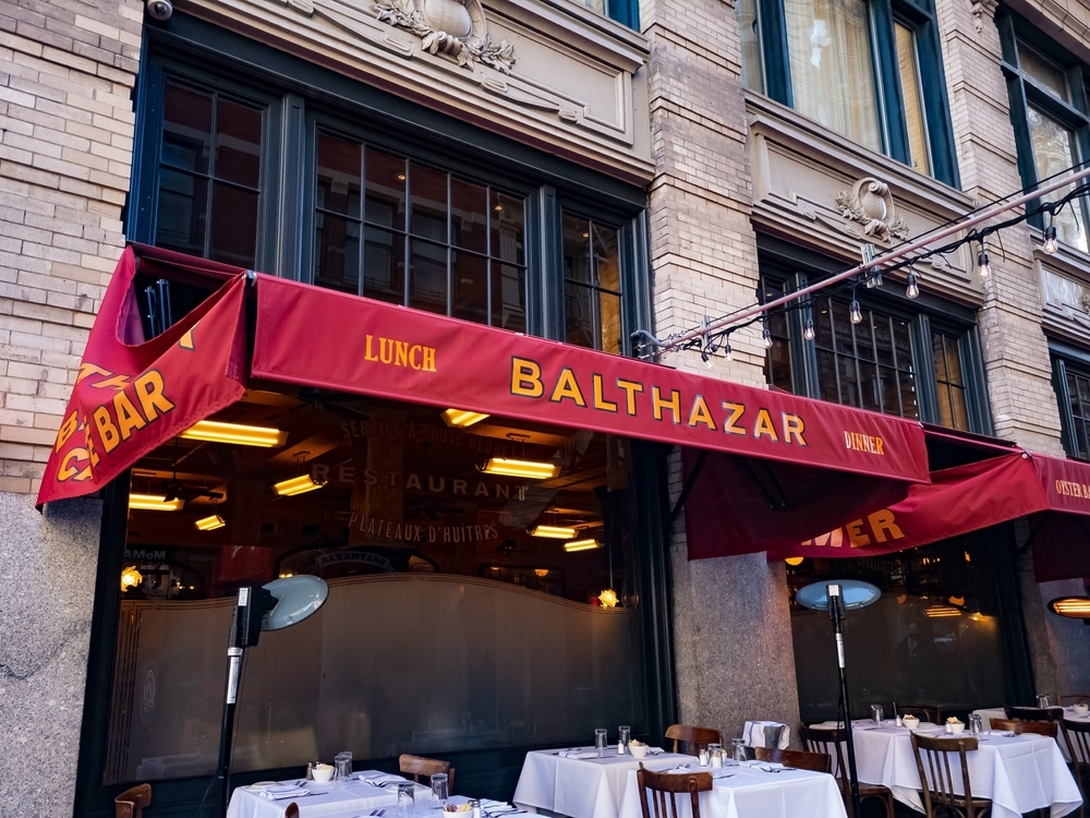 New York, NY, USA - March 13, 2022: Red awning and outdoor seating for Balthazar, a popular French restaurant and bakery in New York City, USA