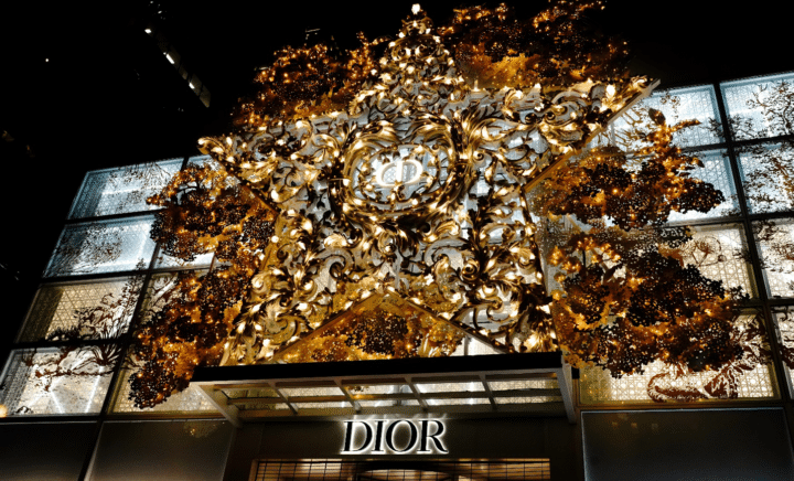A large metallic holiday ornament star and lights above a store reading DIOR