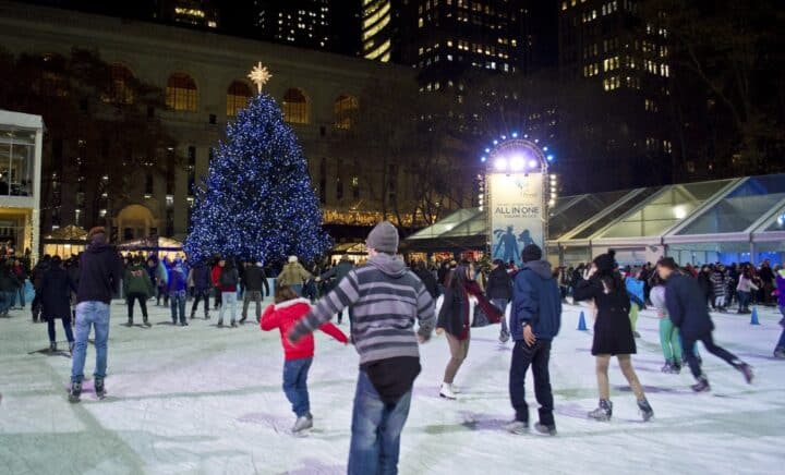 People ice-skating in front of a Christmas tree during a New York City travel guide