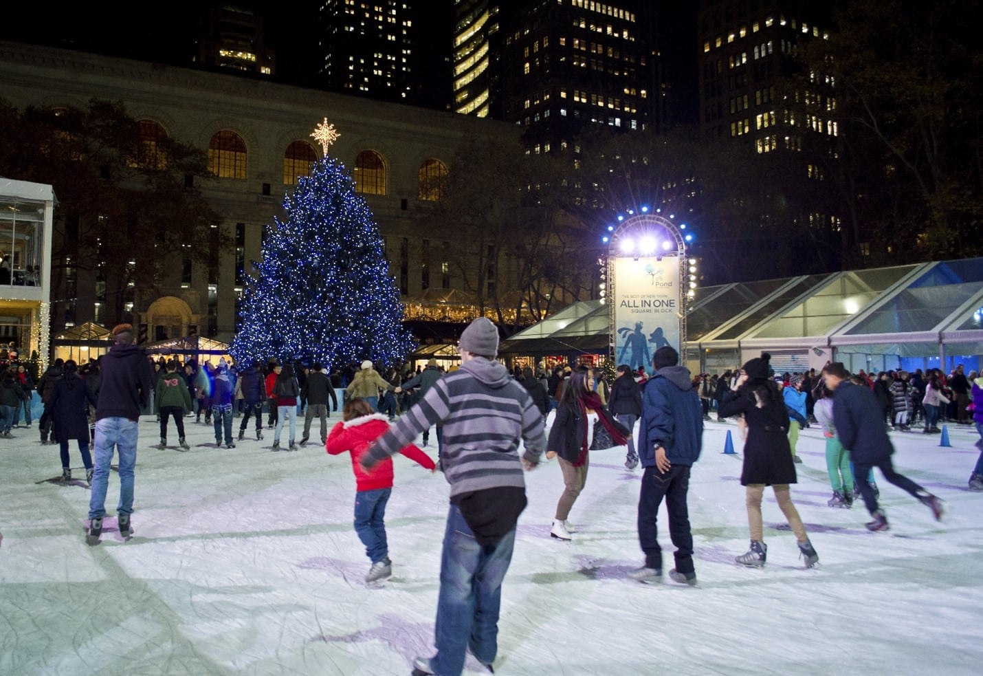 People ice-skating in front of a Christmas tree during a New York City travel guide