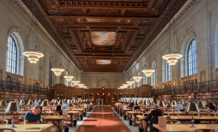 People sitting at desks in a library during a New York City travel guide