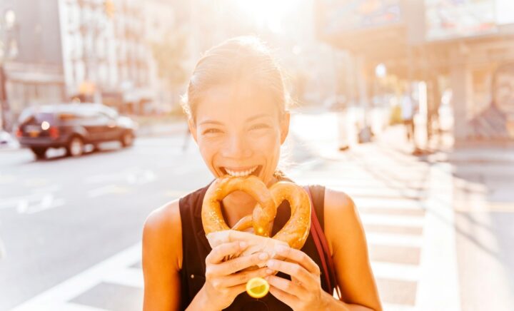 A woman eating a bagel during a New York City travel guide