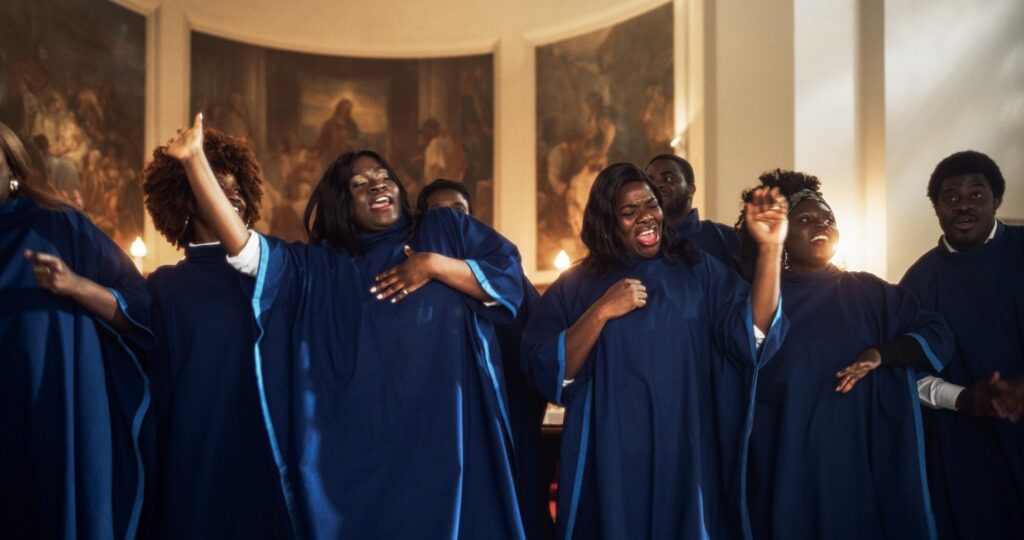 Gospel singers dressed in robes, clapping and singing with joy.