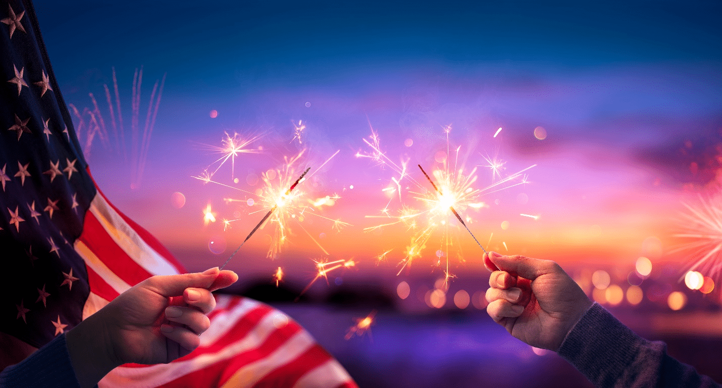 Two hands holding sparklers next to an American flag during a city trip to New York