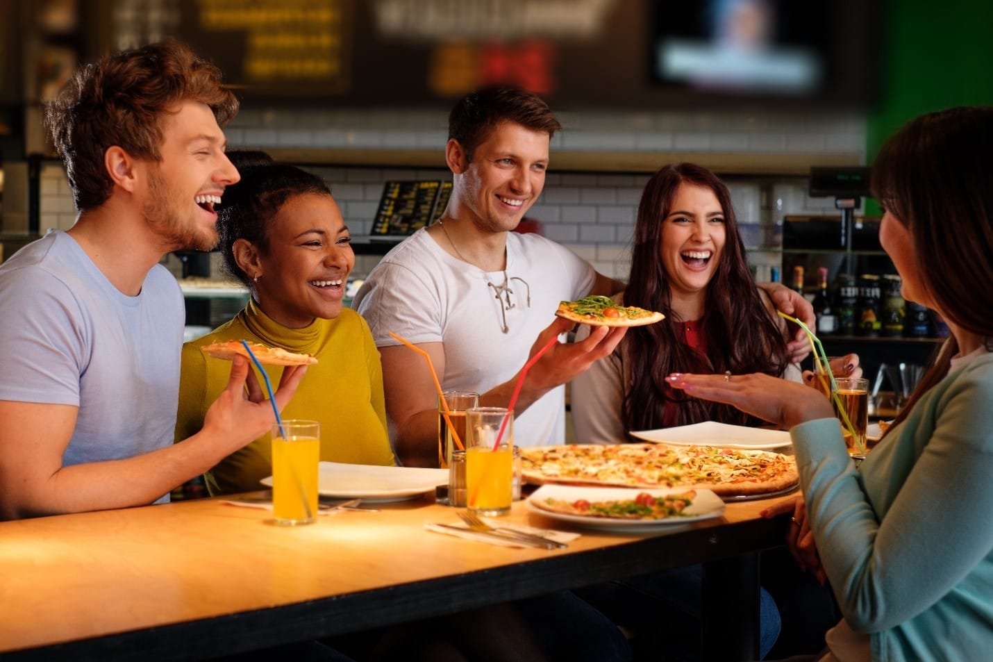 A group of friends eating pizza and drinking during aNew York City travel guide