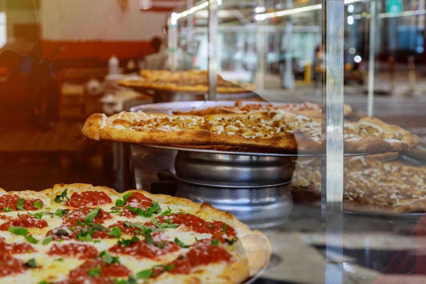 Multiple pizzas on a table seen duringa New York City travel guide