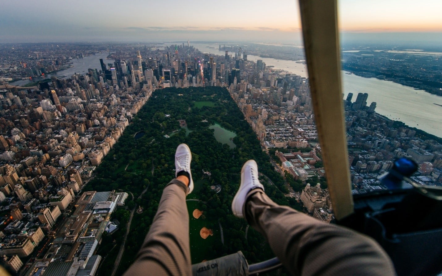 A person dangling their legs above a city duringa New York City travel guide