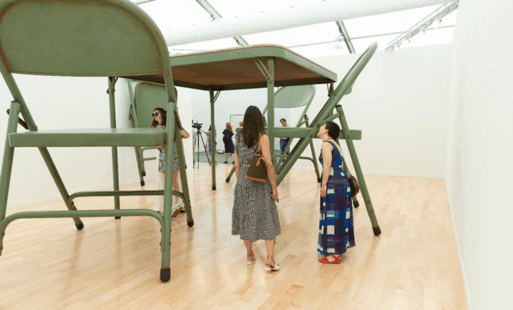 People walking amongst giant chairs during New York City travel guide