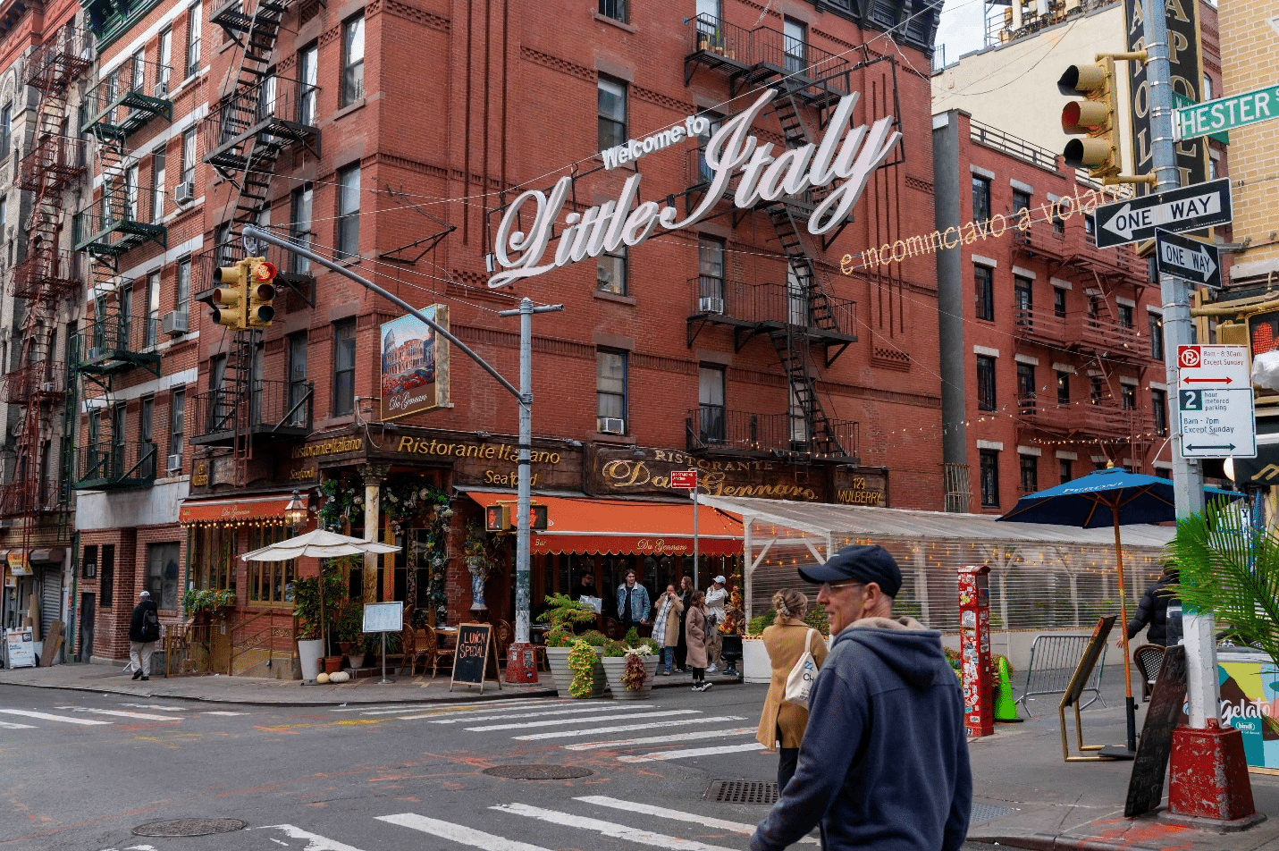 People on a road walking by a large sign for Little Italy during a city trip to New York