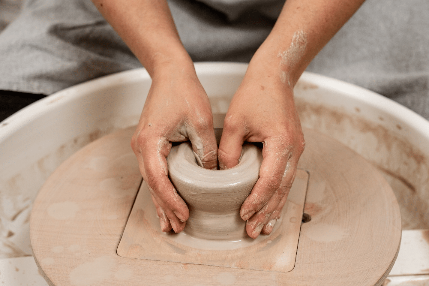 A person molding clay on a pottery wheel during a New York City travel guide