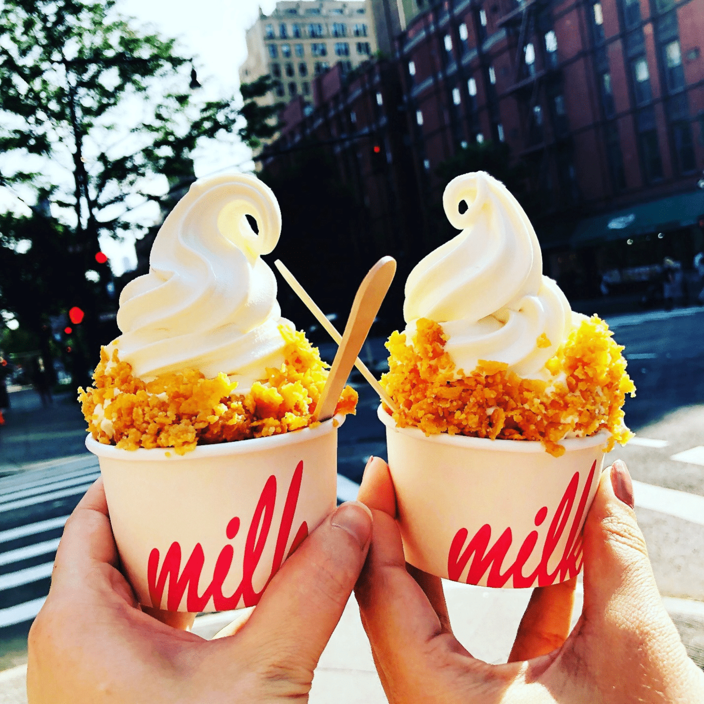 Two hands holding up ice cream cups with cereal in it during a New York City travel guide