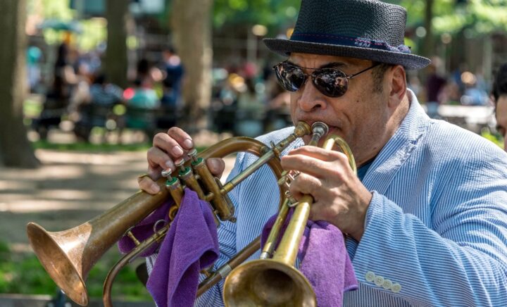 Un hombre tocando trompetas dobles en un parque durante un viaje a la ciudad de Nueva York.