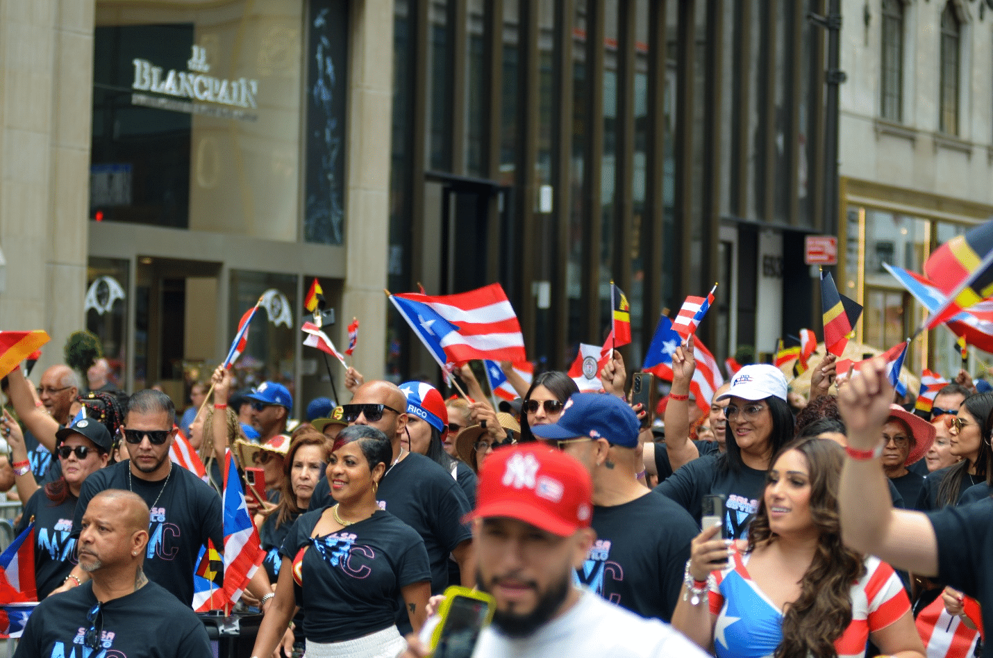 A crowd of people walking through fifth Avenue in Puerto Rican colors