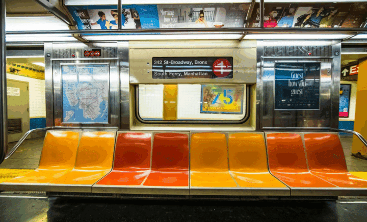 Inside a New York City subway car showing bright multi-colored seats.