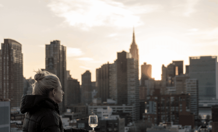 A woman holding a wine glass in front of the NYC skyline