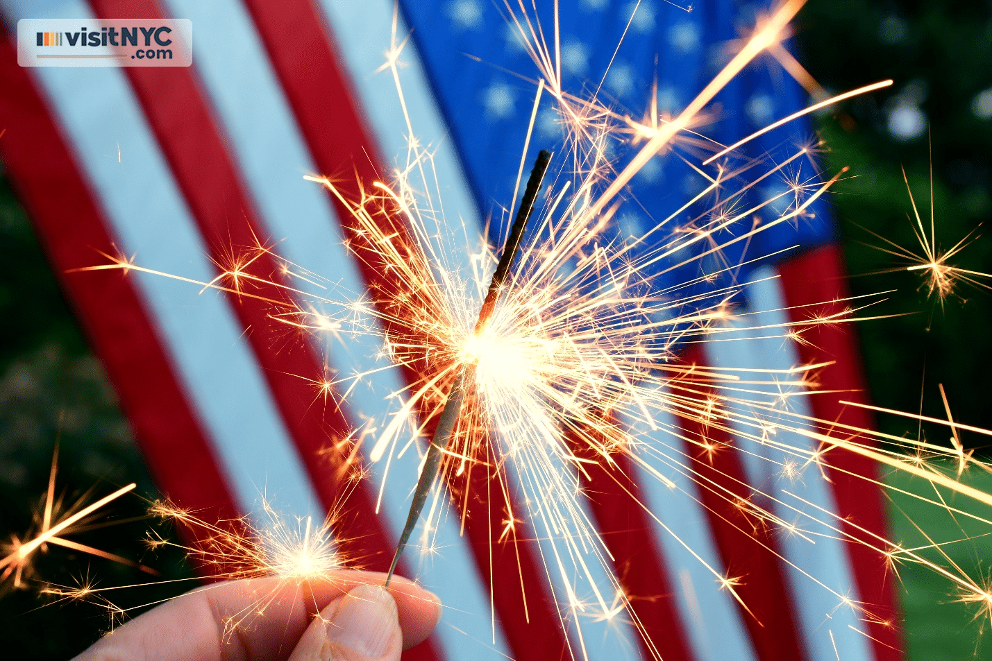 A person holding a sparkler in front of a US flag