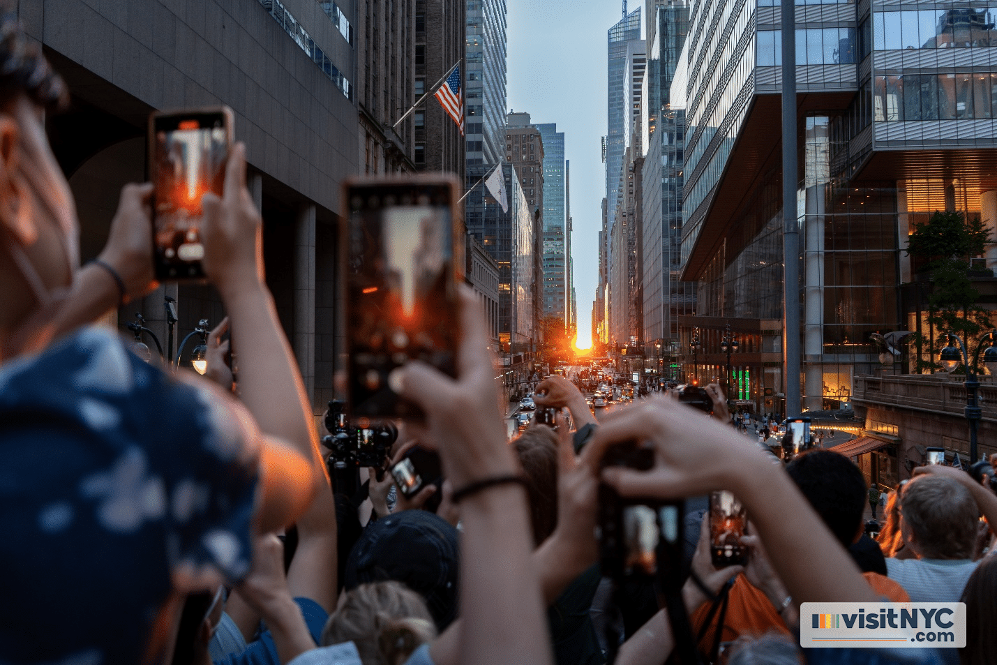 People taking pictures of the sun directly in the middle of two buildings