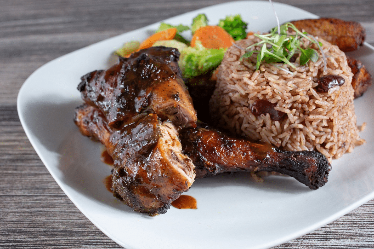 A plate of jerk chicken with rice and beans