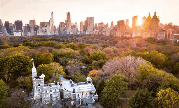 Belvedere Castle and park at sunset, with city buildings behind.