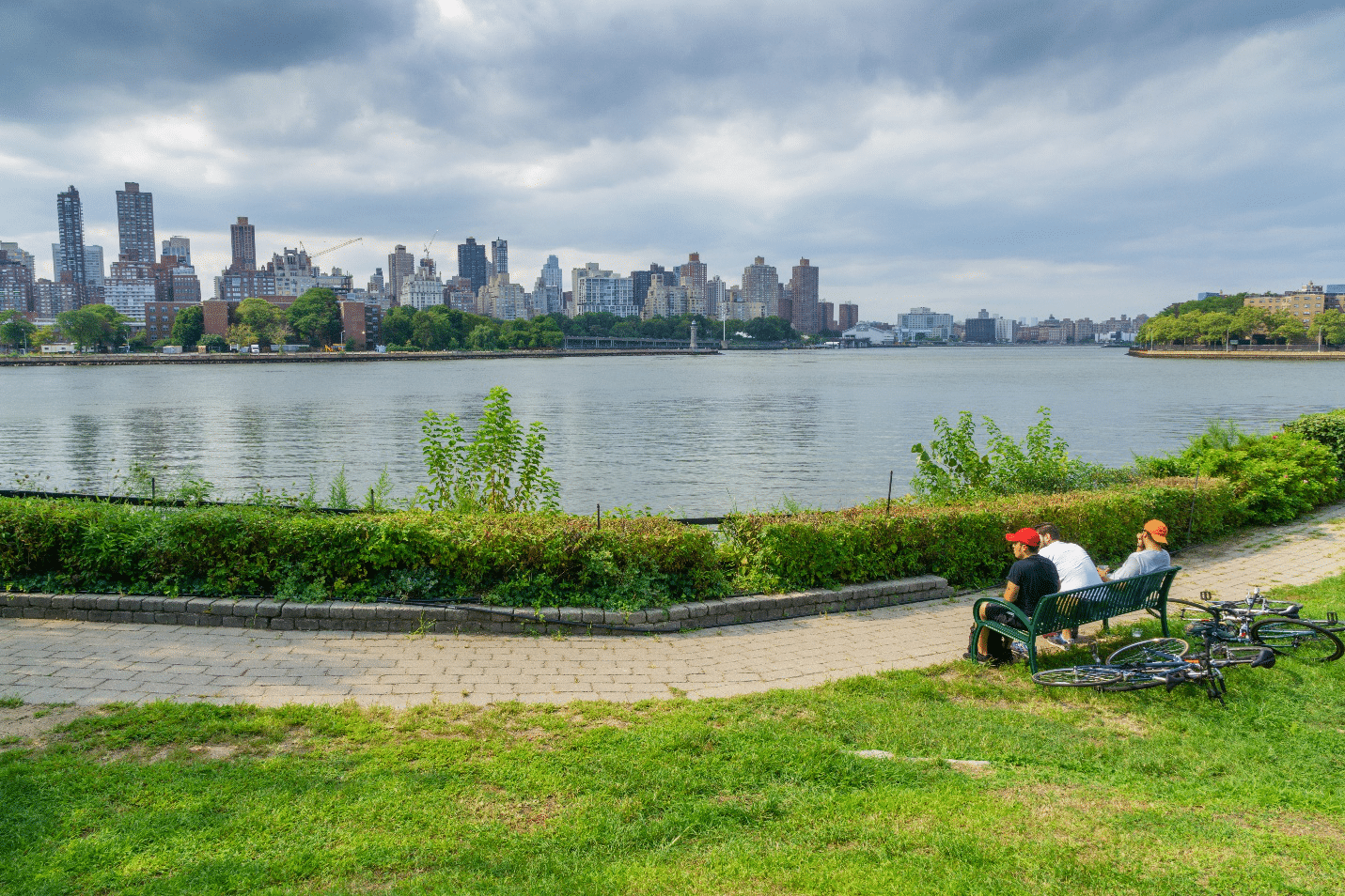 Two people sitting on a bench by the water in Socrates Sculpture Park