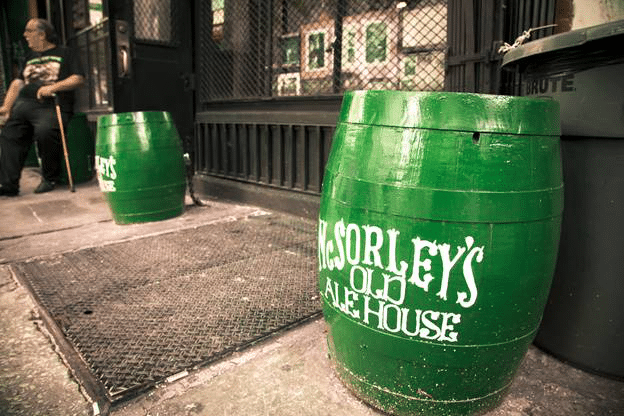 Green barrels with McSorley's Old Ale House logo on the sidewalk.
