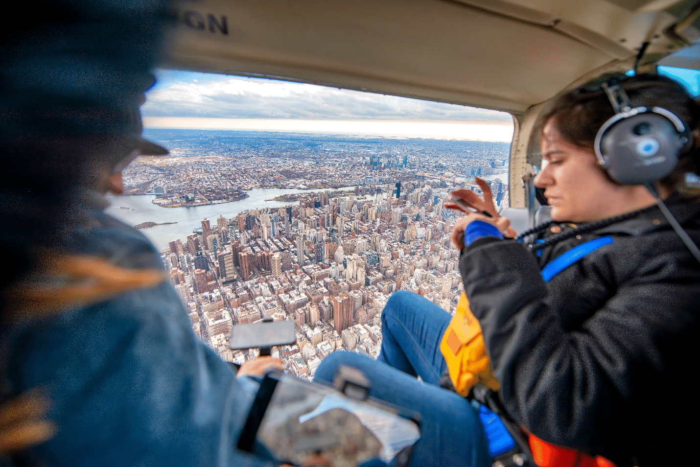 People sitting in a helicopter taking pictures of the view of the city