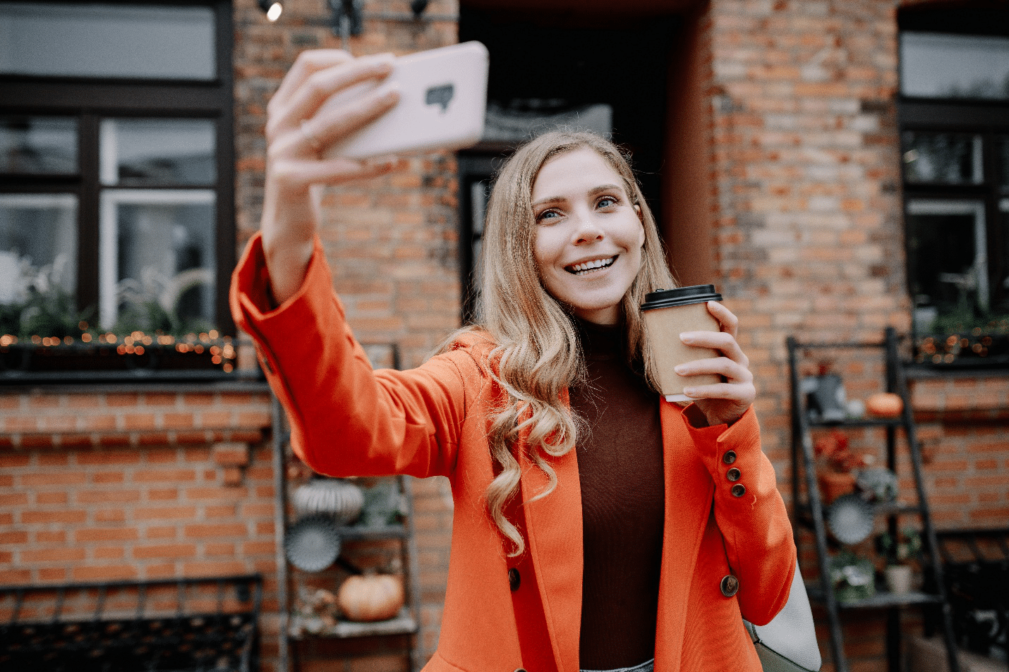 woman taking a selfie while holding a cup of coffee