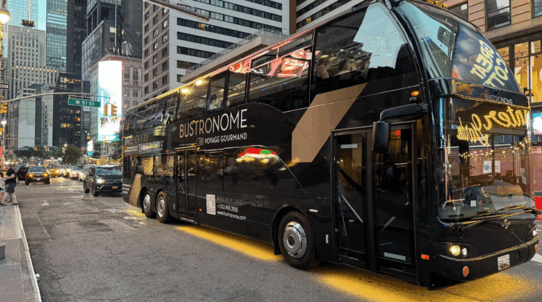 Bustronome NYC glass-roofed bus with guests dining inside while passing New York City landmarks.