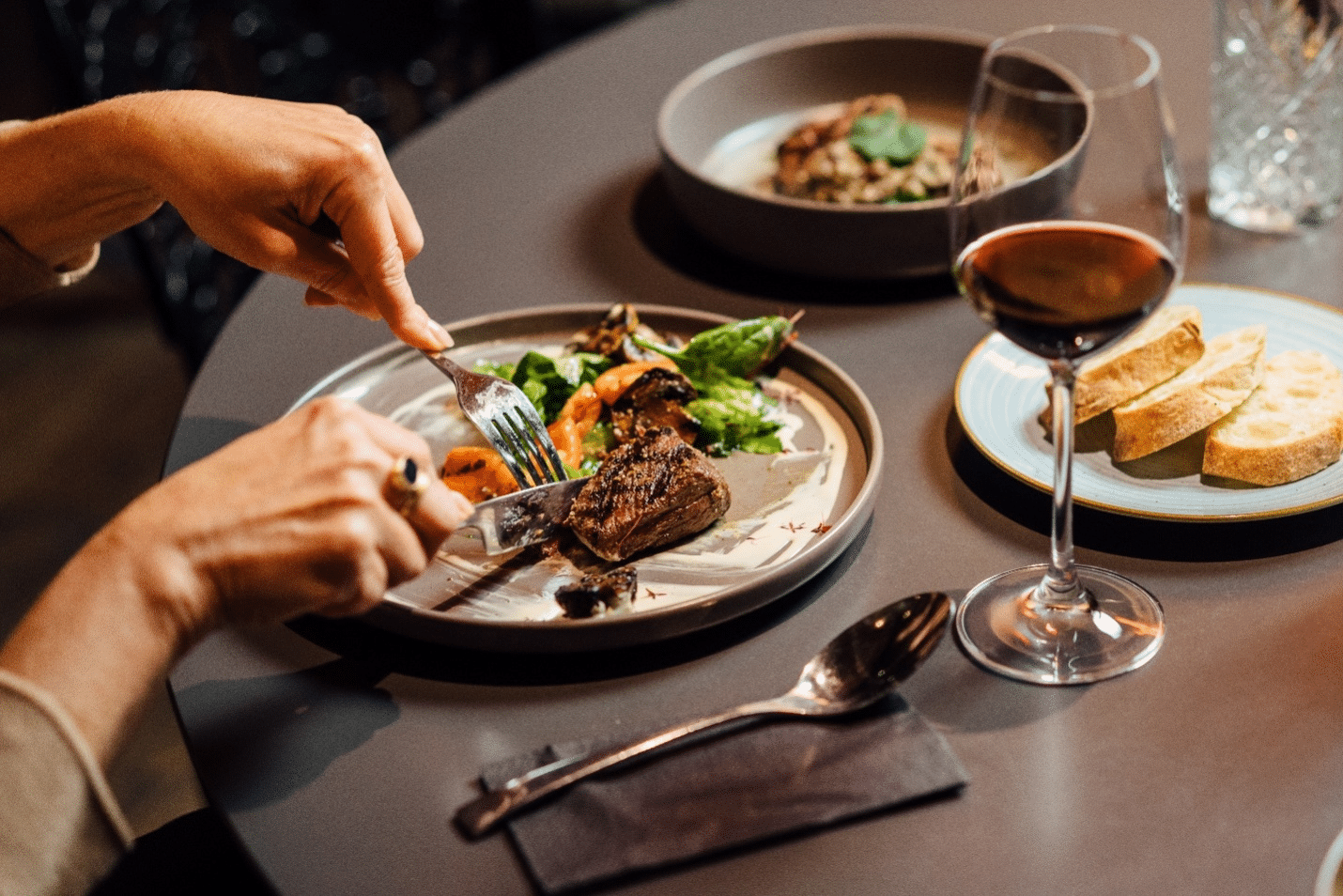 A person cutting a steak on a plate at a restaurant