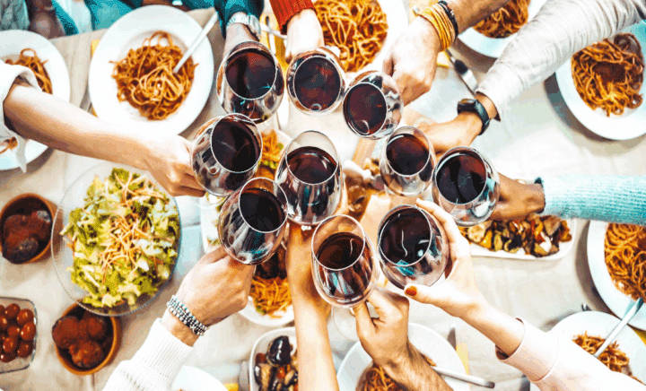 group of friends enjoying red wine and toasting at a lively gathering