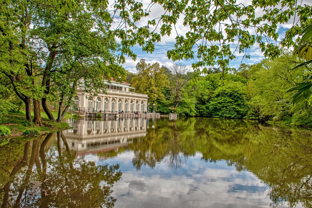 The Prospect Park Boathouse in Brooklyn, New York, surrounded by fall foliage, reflecting on the lake.