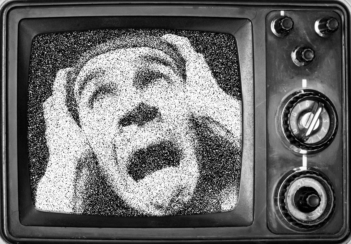 Terrified man appearing on a vintage television screen in a dark setting.